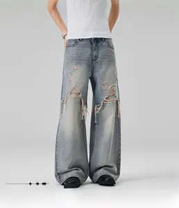 Detail view of light blue loose straight fit denim jeans with distressed ripped knee design