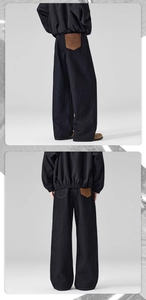 Detail of dark denim wide leg trousers featuring a brown suede patch with MS embroidery
