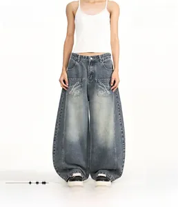 Dettaglio di jeans baggy taglio curvo con grandi tasche e ricamo bianco su modello