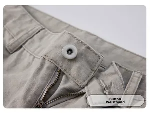 Gros plan de la taille boutonnée et du zip métallique sur un pantalon cargo kaki