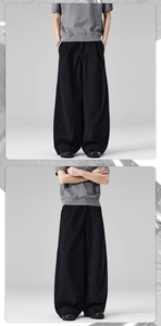 Detailed view of men's wide-leg black cotton trousers with high-waist pleated design