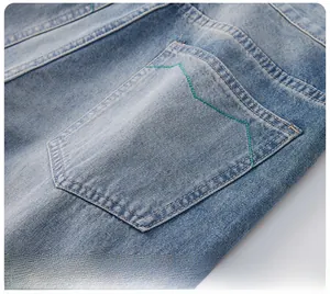 Detail der hellblauen Jeans mit markanter grüner Kontrastnaht an der Gesäßtasche