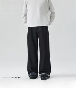 Detail shot of black loose straight jeans featuring plaid lining at the rolled cuffs