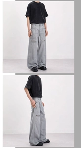 Detail view of light gray wide-leg cargo pants with large side pockets and metal zippers