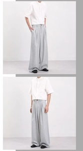 Detail view of light grey wide-leg trousers with high waist pleats and premium drape texture