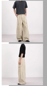 Dettaglio dei pantaloni cargo kaki con grandi tasche e taglio ampio a gamba larga