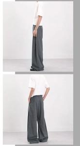 Detailed view of grey-green plaid wide-leg pants showing pleated slit hem and draped fabric