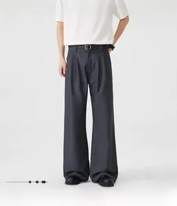 Detail of dark gray wide-leg trousers featuring waist pleats and a matching belt