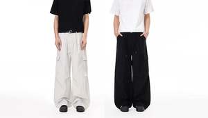 Detail of loose-fit cargo pants with large flap pockets and drawstring waist in two colors