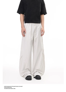 Detail of light grey wide-leg cargo pants featuring pleated knees and drawstring waist
