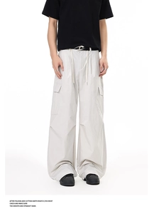 Detail of light gray tactical cargo pants with large side flap pocket and D-ring belt
