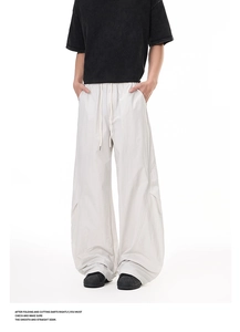 Detail view of lightweight white wide-leg trousers with drawstring waist and stacked hem
