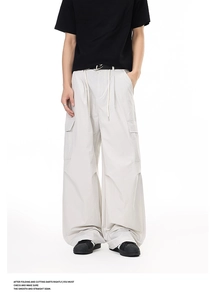 Detail of light gray wide-leg cargo pants featuring large flap pockets and drawstring waist