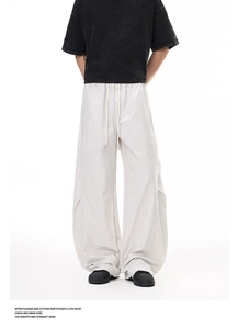 Close-up of light grey oversized cargo pants with drawstring waist and pleated knee details