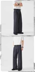 Detail view of dark grey straight-leg trousers with elegant pleats and a black belt