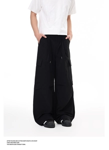 Detail of black wide-leg cargo pants featuring adjustable drawstring waist and side flap pockets