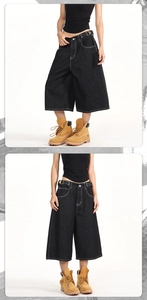 Detail of black denim carpenter shorts featuring white contrast stitching and wide-leg cut