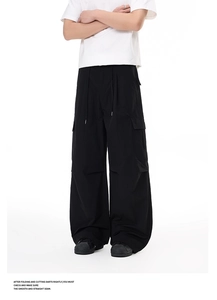 Detail view of black cargo pants featuring wide-leg cut and large functional flap pockets