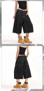 Detail of dark gray denim wide-leg pants featuring white stitching and red embroidery