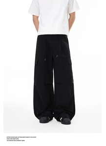 Detail view of black cargo pants featuring wide-leg cut and large side flap pockets