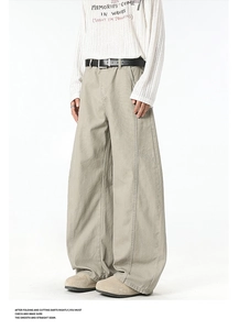 Detail of khaki wide-leg trousers with contrast stitching, cargo pockets and leather belt