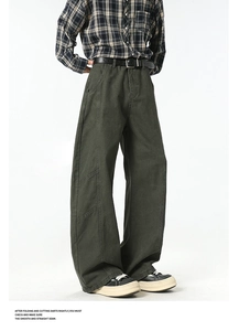 Detail view of dark green cargo pants with contrast stitching and wide-leg silhouette