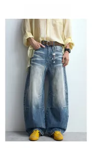 Detail of loose-fit curved jeans with vintage whiskers wash and distressed denim texture