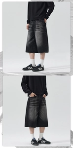 Detail shot of vintage black washed denim shorts with whiskers and street style wide leg