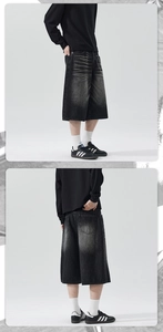 Detail of vintage washed black denim shorts featuring loose wide-leg fit and faded textures