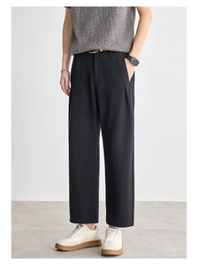 Detail of men's black straight-leg trousers with textured fabric and drape effect