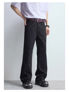 Détail d'un jean slim noir en denim avec textures usées et motifs de moustaches de chat