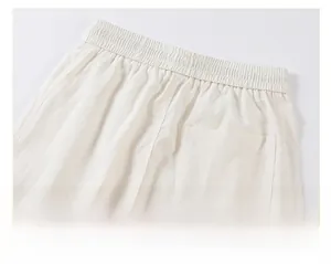 Detail of elastic drawstring waistband and textured fabric on off-white casual pants