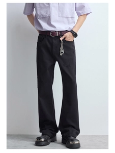 Détail d'un jean évasé noir avec des trous aux genoux et une texture en denim délavé