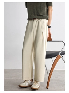 Detailed view of cream-colored wide-leg trousers with a draped texture and leather belt