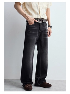 Détail d'un jean évasé noir délavé pour homme avec texture vintage usée et coupe droite élégante