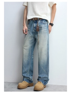 Detail of vintage blue washed jeans featuring straight leg cut and leather belt styling