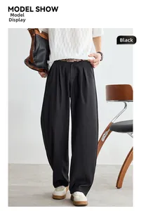 Détail d'un pantalon noir plissé minimaliste japonais avec une ceinture en cuir marron