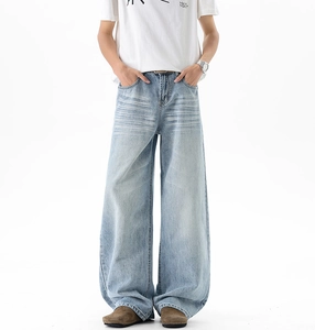 Detail view of light blue washed denim jeans featuring cat-whisker fading and wide leg cut