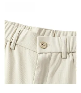 Detailed macro view of cream corduroy pants showing elastic waistband and resin button
