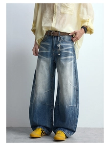 Detail of blue wide-leg jeans featuring vintage wash whiskers and diagonal seam stitching