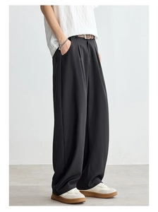 Détail du pantalon noir à jambe droite avec un tombé élégant et des plis sur le devant
