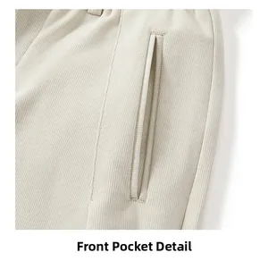 Detailed view of the front pocket and textured ribbed fabric on beige straight trousers