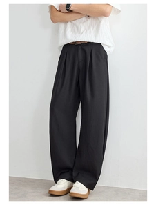 Détail du pantalon noir à jambes larges avec taille haute plissée et texture naturelle