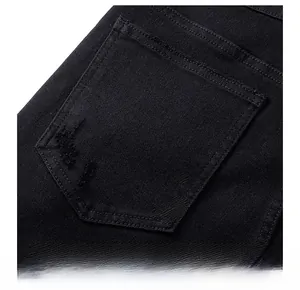 Détail macro de la poche arrière en denim noir avec bord usé et texture sergé