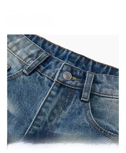 Detail show of metal button and yellow double stitching on washed blue denim waistline