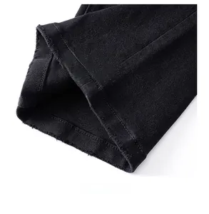 Gros plan d'un jean noir montrant l'ourlet brut effiloché et la texture du denim
