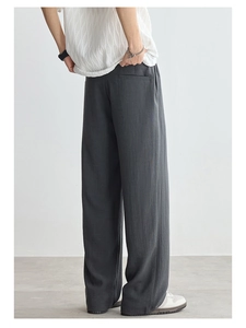 Detail view of dark grey wide-leg trousers showing natural texture and back pocket design