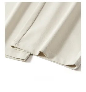 Detail shot of beige textured trousers showing smooth hem stitching and vertical fabric ribs
