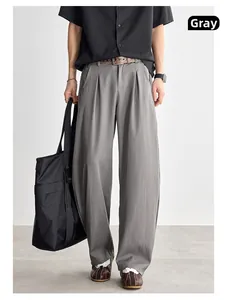 Détail du pantalon gris à jambes larges, tissu drapé de qualité et taille haute plissée