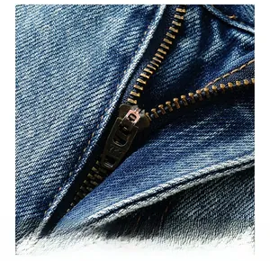Detail of high-quality YKK metal zipper on blue washed denim jeans with durable stitching
